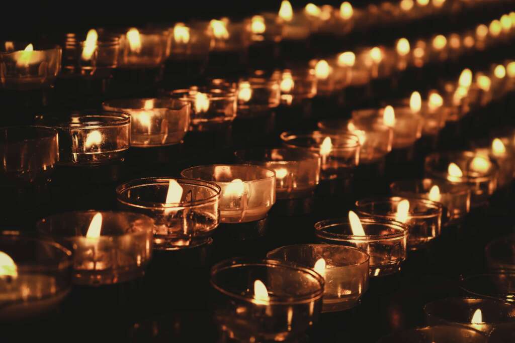 Rows of glowing candles in the dark, symbolizing recovery and shadow work in real life—bringing light to the shadow with compassion.